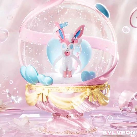 Step into a whimsical world of magic with this officially licensed Pokémon Sylveon Dreamy Crystal Ball Figure! This stunning collectible showcases the beloved Fairy-type Evolution, Sylveon, perfectly posed inside a clear, glitter-infused dome.

Set against a pastel heart backdrop and surrounded by floating heart details, the entire figure rests on an elegantly sculpted pink and gold pedestal adorned with decorative bows. It is a breathtaking statement piece designed for dedicated Pokémon collectors and love